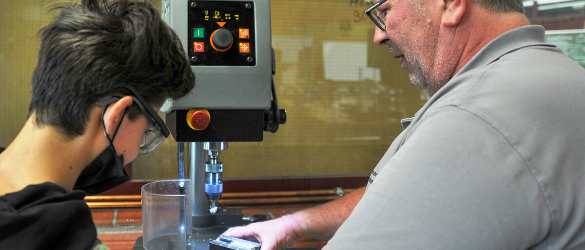 Präzision gefragt: An der Senkmaschine in der Metallwerkstatt zeigt Ausbildungsmeister Michael Becker, wie man Material durch Zerspanung in die richtige Form bringt.