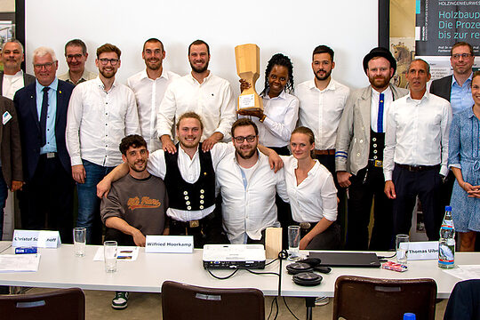 Jurymitglieder, Organisatoren, Gewinnerinnen und Gewinner mit Pokal und Holzhütte.