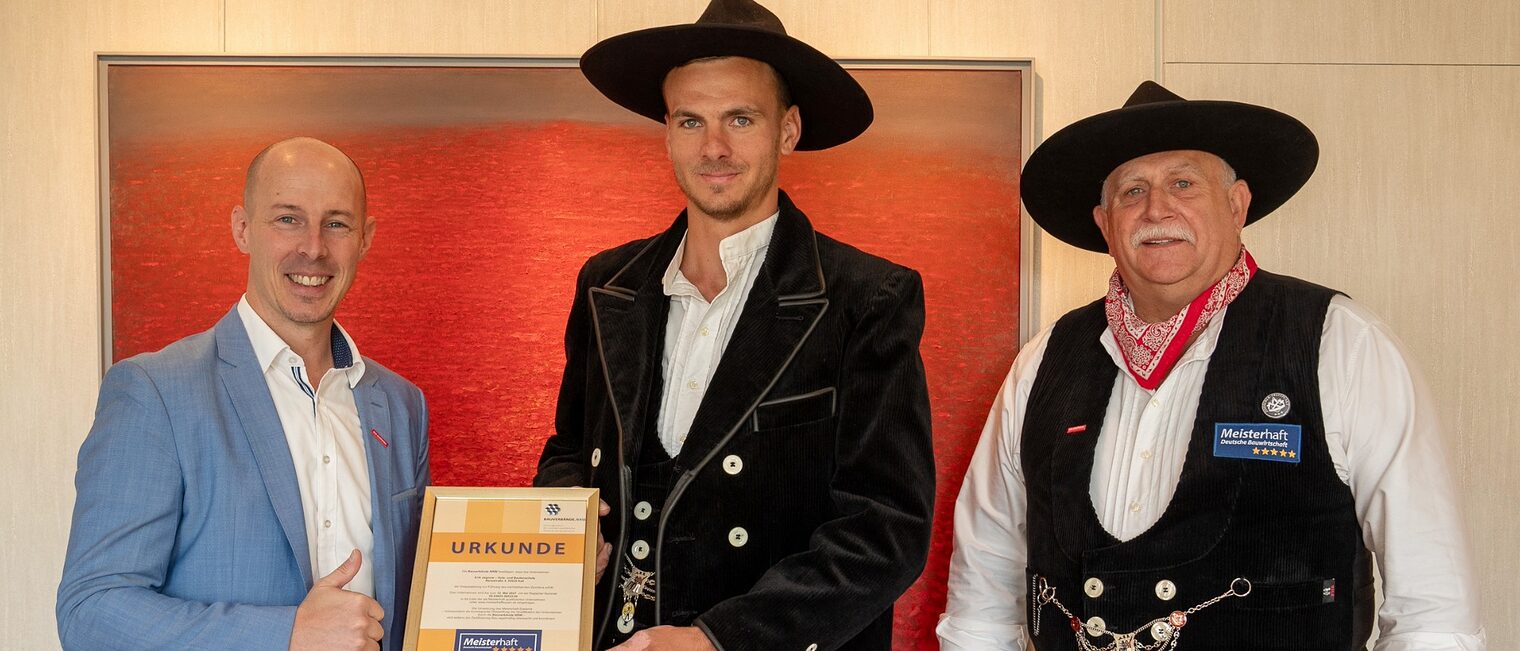 Ein besonderer Moment für Erik Jagnow: HWK-Präsident Marco Herwartz überreicht die „Meisterhaft“-Urkunde. In Begleitung seines Vaters Peter trug er bei der Übergabe die traditionelle Zimmermannskluft