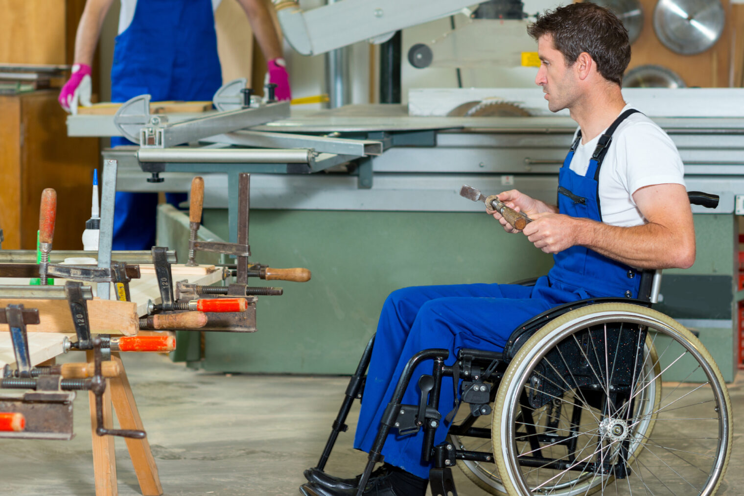 Mann im Rollstuhl in einer Werkstatt.