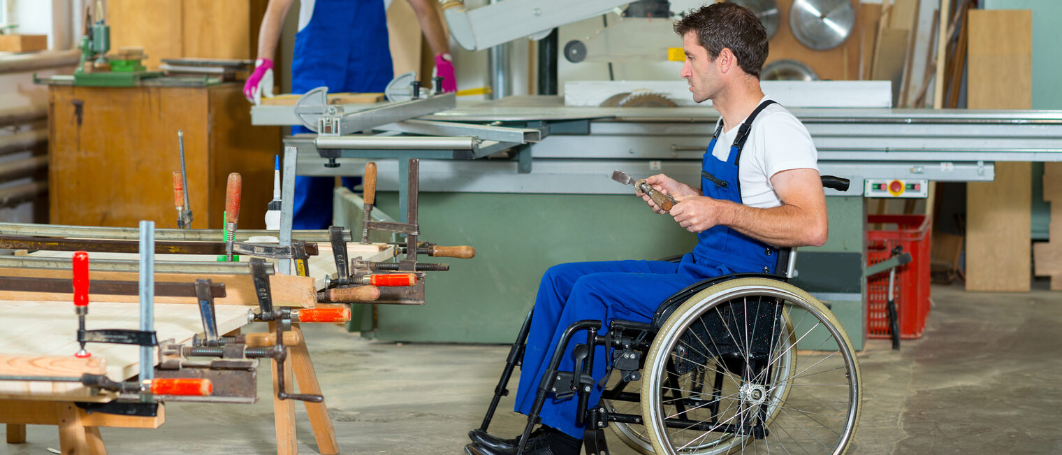 Mann im Rollstuhl in einer Werkstatt.