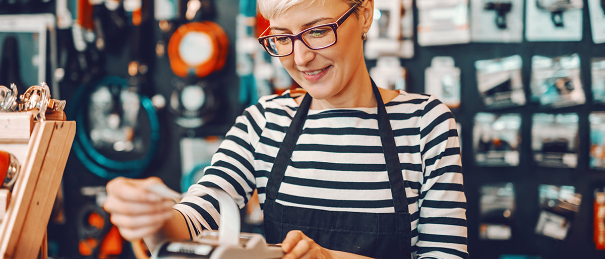 Smiling Caucasian female worker with short blonde hair and eyeglasses using cash register while standing in bicycle store. Schlagwort(e): counter, cashier, woman, retail, press, payment, cash counter, cashier machine, store, seller, consumerism, bill, payment terminal, paying, register, cash, sales person, saleswoman, staff, cash register, indoors, financial, contemporary, worker, employee, equipment, check out, job, commercial, beautiful, billing counter, cashier counter, cashier desk, purchase, finance, sale, bicycle, workplace, cyclist, owner, profession, son, selling, city-bike, gear, alternative, bike, working, smiling, shop