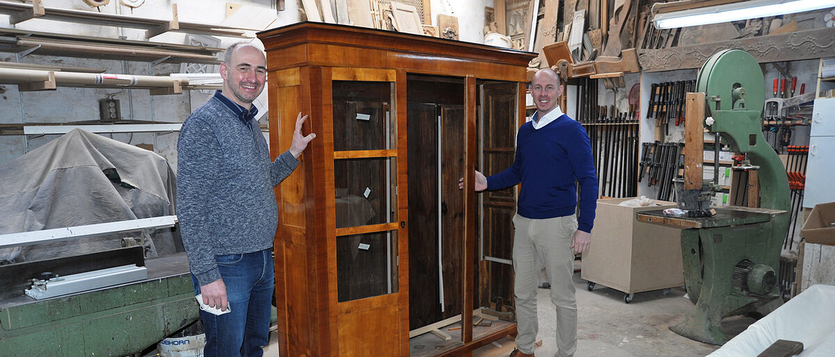 Kostbarer Schrank, von Meisterhand restauriert: Marcus Schiffers (l.) und Marco Herwartz vor dem mit Schellack überzogenen Familienstück. Foto: Elmar Brandt Kostbarer Schrank, von Meisterhand restauriert: Marcus Schiffers (l.) und Marco Herwartz vor dem mit Schellack überzogenen Familienstück. Foto: Elmar Brandt